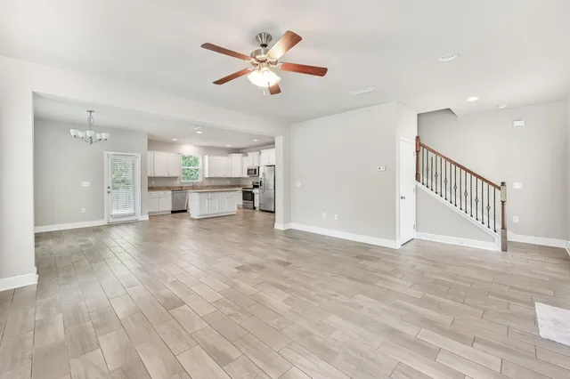 a view of a livingroom with a fireplace a ceiling fan and wooden floor
