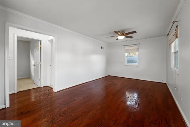 an empty room with wooden floor chandelier fan and windows