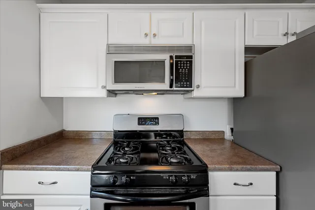 a kitchen with granite countertop a stove and a white cabinets