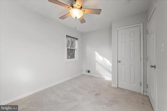an empty room with chandelier fan and windows