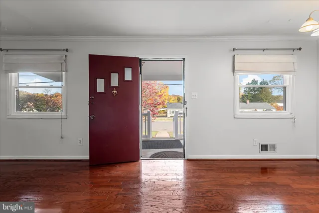 a view of an empty room with window and wooden floor