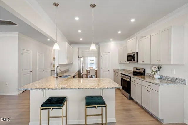 a large kitchen with kitchen island white cabinets and stainless steel appliances