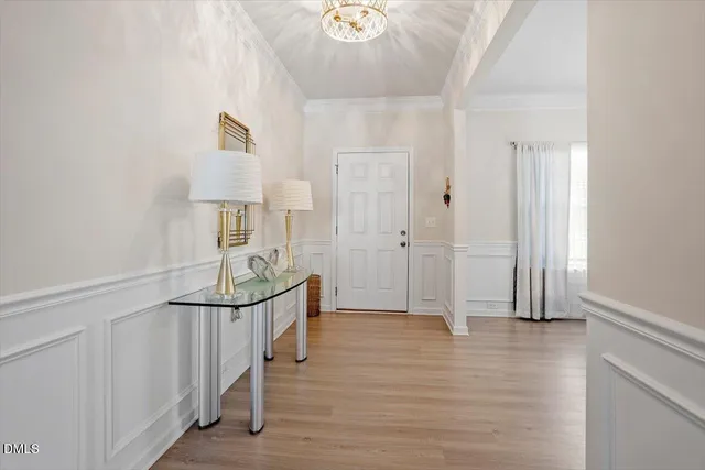 a view of a dining room and livingroom with furniture wooden floor a chandelier