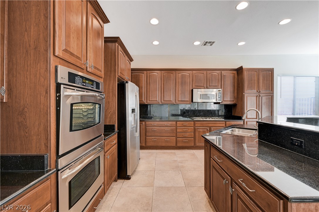 6761 Clay TABLET Street Las Vegas, NV 89149 - Photo 24 of 73 Rich wood cabinetry paired with dark granite countertops and stainless steel appliances defines this kitchen.