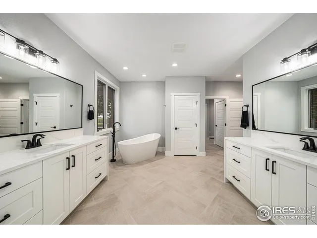 a large bathroom with a double vanity sink a large mirror and a bathtub