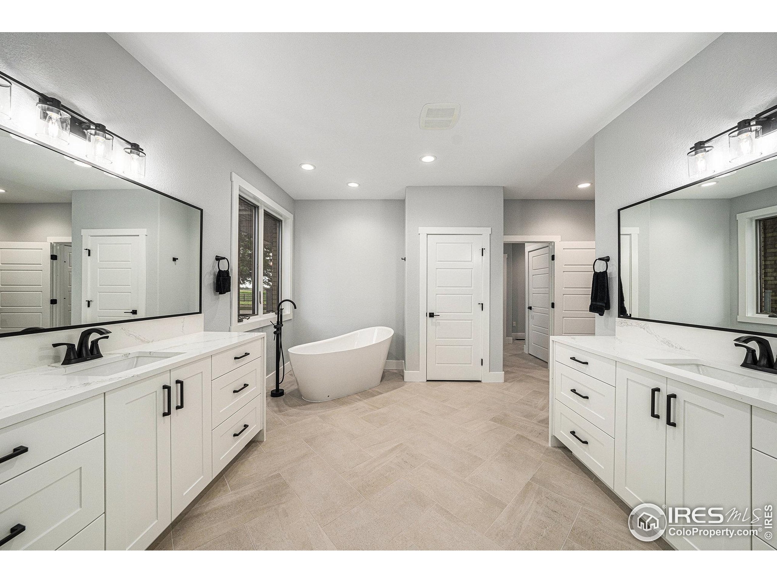 796 Abrams Way Berthoud, CO 80513 - Photo 11 of 40 a large bathroom with a double vanity sink a large mirror and a bathtub