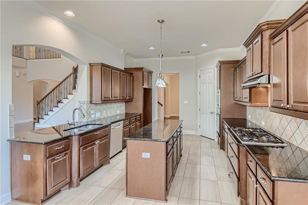 3822 Remington Road Cedar Park, TX 78613 - Photo 10 of 31 a kitchen with stainless steel appliances granite countertop a stove top oven a sink dishwasher and a refrigerator with wooden cabinets