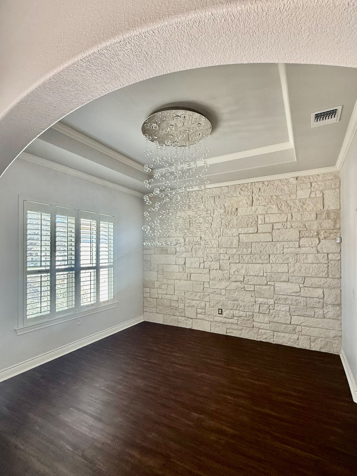 231 Marbella Way Georgetown, TX 78633 - Photo 14 of 40 An inviting interior space features a dramatic chandelier and a textured stone accent wall.