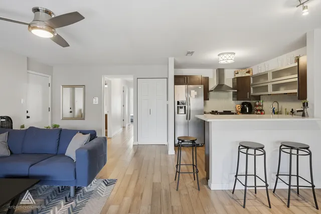a living room with stainless steel appliances kitchen island granite countertop furniture and a refrigerator