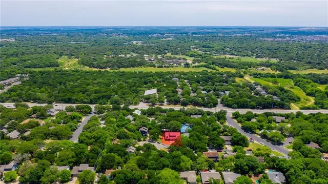 an aerial view of residential houses with outdoor space and trees