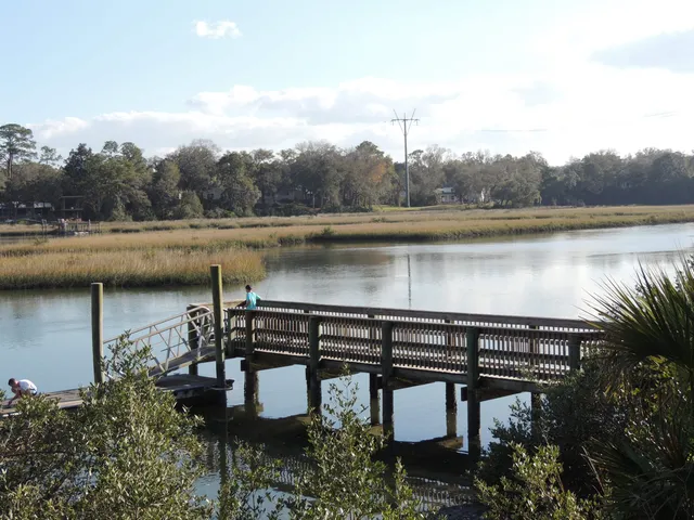 a view of a lake with a bench and trees in the background