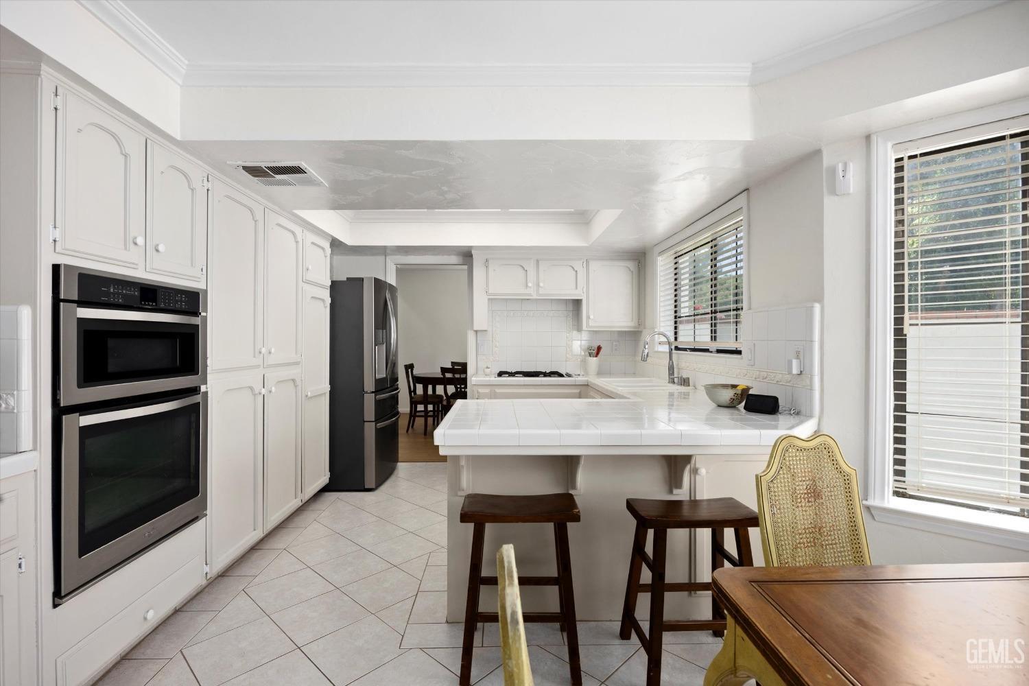 Undisclosed Address Bakersfield, CA 93309 - Photo 18 of 48 a kitchen with stainless steel appliances granite countertop a stove a refrigerator a microwave oven with white cabinets and wooden floor