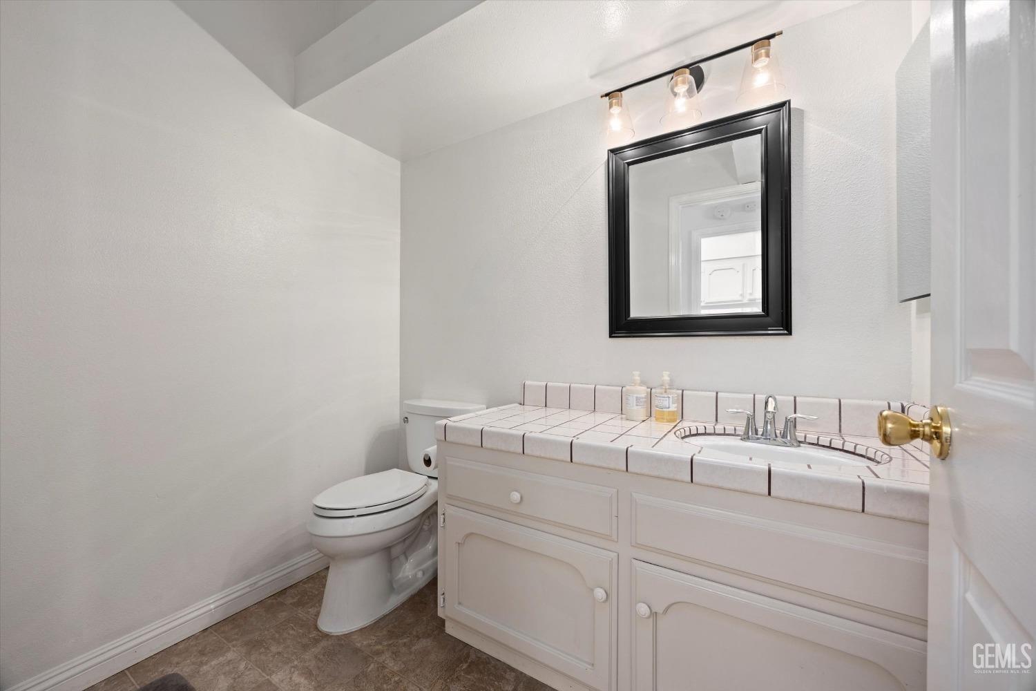 Undisclosed Address Bakersfield, CA 93309 - Photo 31 of 48 a bathroom with a toilet a sink and mirror