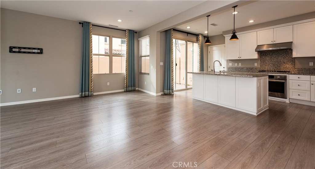 107 Desert Lotus Irvine, CA 92618 - Photo 2 of 21 a kitchen with stainless steel appliances granite countertop a refrigerator a sink dishwasher a stove and white countertops with wooden floor