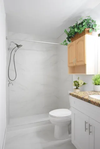 a bathroom with a granite countertop sink toilet and shower