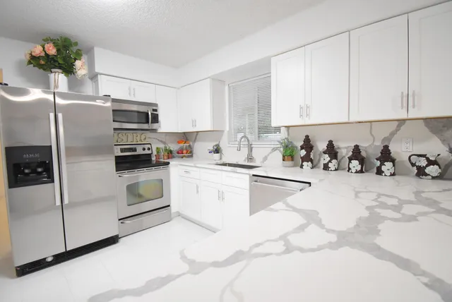 a kitchen with granite countertop white cabinets and white appliances