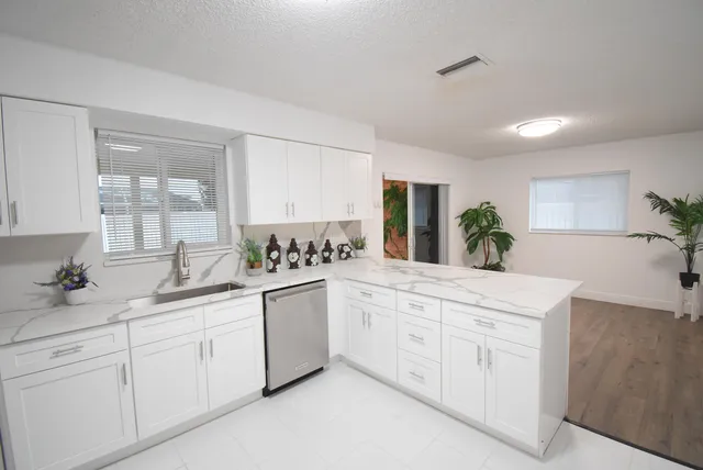 a kitchen with white cabinets and sink