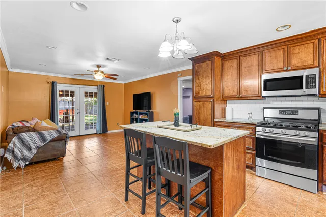 a kitchen with stainless steel appliances granite countertop a stove top oven a sink dishwasher a dining table and chairs with wooden floor