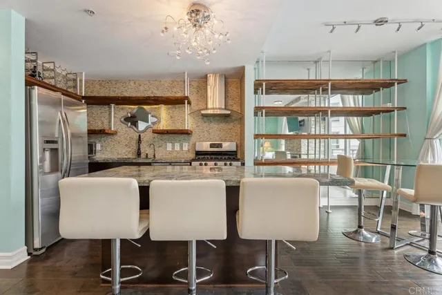 a kitchen with kitchen island a dining table chairs cabinets and stainless steel appliances