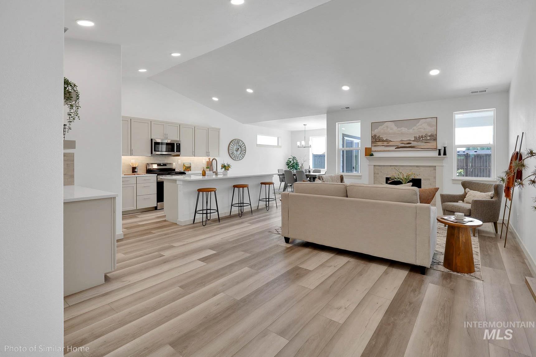 389 West Gleason Court Meridian, ID 83646 - Photo 2 of 6 Living room with light wood finished floors, vaulted ceiling, recessed lighting, a fireplace, and a chandelier