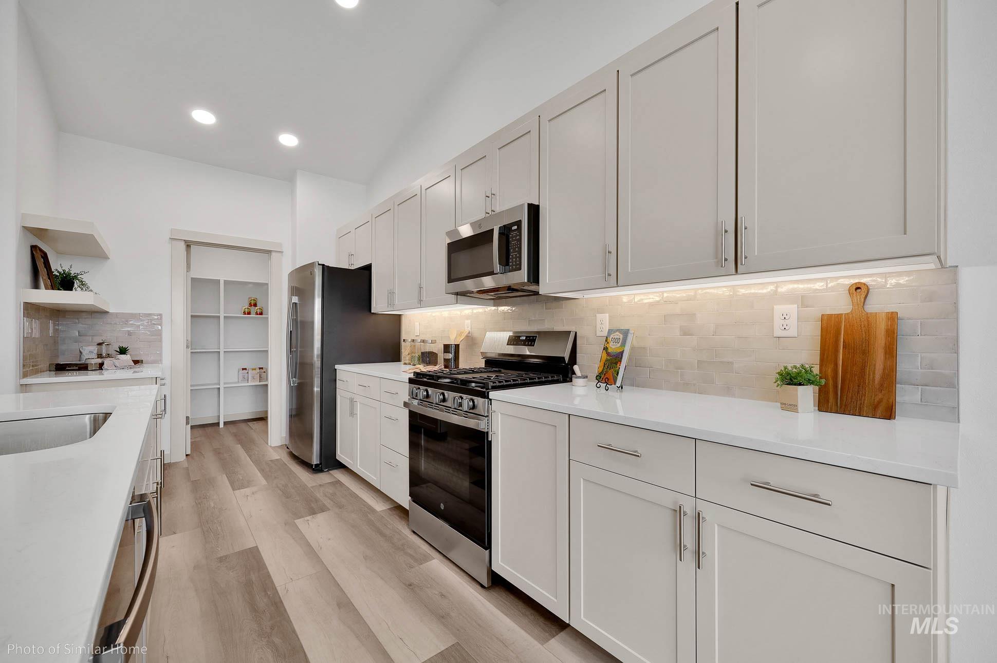 389 West Gleason Court Meridian, ID 83646 - Photo 3 of 6 Kitchen featuring appliances with stainless steel finishes, decorative backsplash, light wood-style floors, light stone counters, and recessed lighting