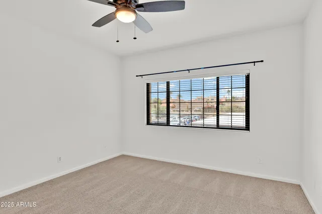 an empty room with a window and a ceiling fan