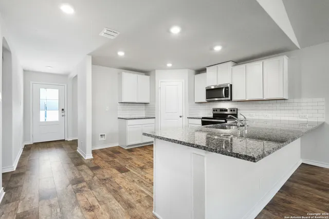 a kitchen with granite countertop stainless steel appliances a sink a refrigerator a stove a microwave and cabinets