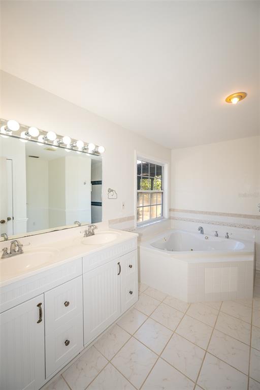 8077 Lake Hatchineha Road Haines City, FL 33844 - Photo 21 of 45 a spacious bathroom with a double vanity sink mirror and bathtub