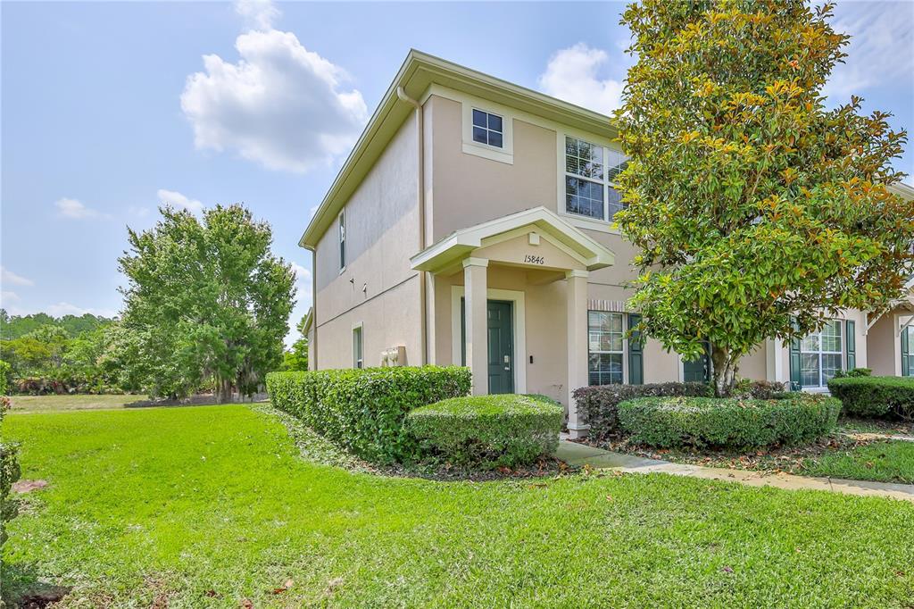 a view of a white house with a big yard and potted plants