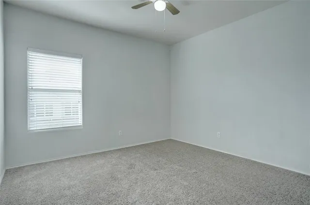 an empty room with a window and a fan