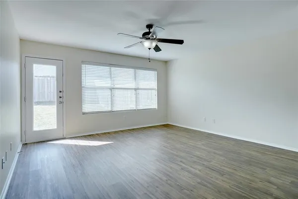 an empty room with wooden floor chandelier and windows