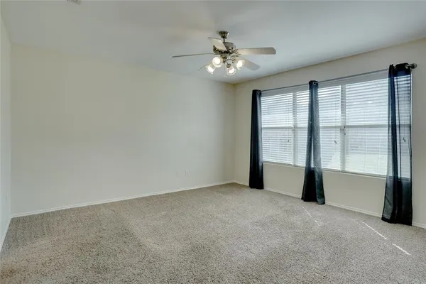 a view of an empty room with chandelier fan and fire place