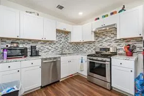 a kitchen with cabinets stainless steel appliances a sink and wooden floor