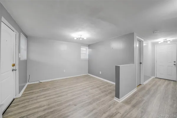 a view of hallway with a room and wooden floor