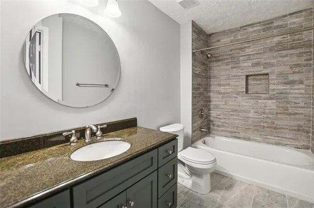 a bathroom with a granite countertop sink toilet a mirror and shower