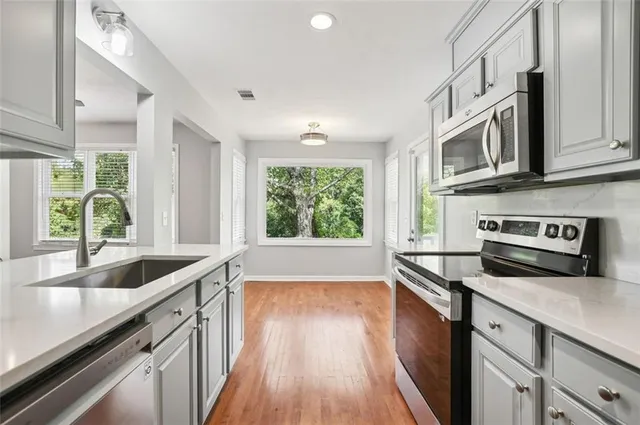 a kitchen with stainless steel appliances granite countertop a sink a stove and a wooden floors