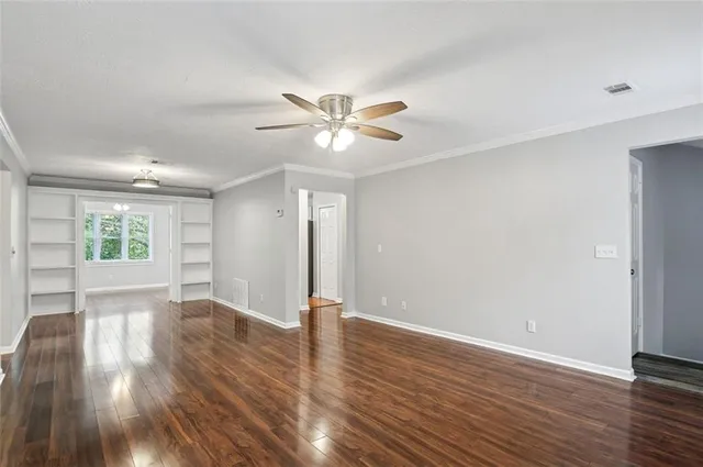 a view of an empty room with window and wooden floor