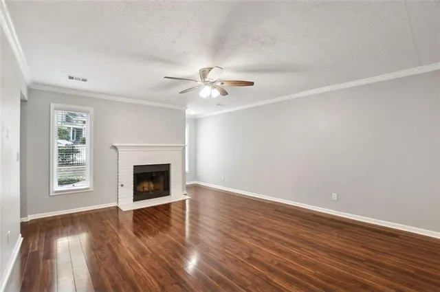 an empty room with wooden floor a chandelier fan and windows