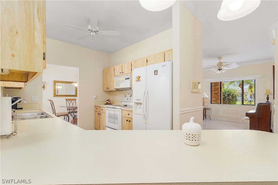 17601 Laurel Valley Road Fort Myers, FL 33967 - Photo 17 of 25 a kitchen with stainless steel appliances kitchen island granite countertop a refrigerator a sink a stove a dining table and chairs with wooden floor