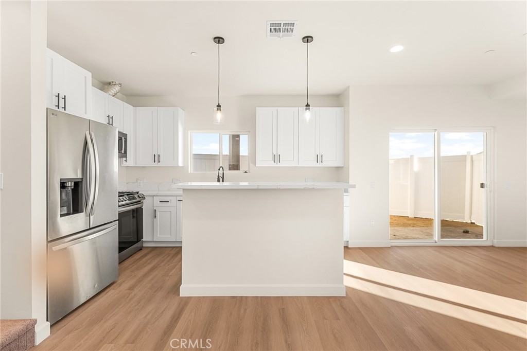 904 South Hert Street Colton, CA 92324 - Photo 16 of 35 a kitchen with stainless steel appliances granite countertop a refrigerator a sink a stove and white cabinets with wooden floor