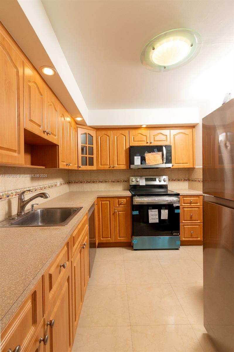 447 Northeast 195th Street, Unit 217 Miami, FL 33179 - Photo 14 of 22 a kitchen with stainless steel appliances a stove cabinets and a sink