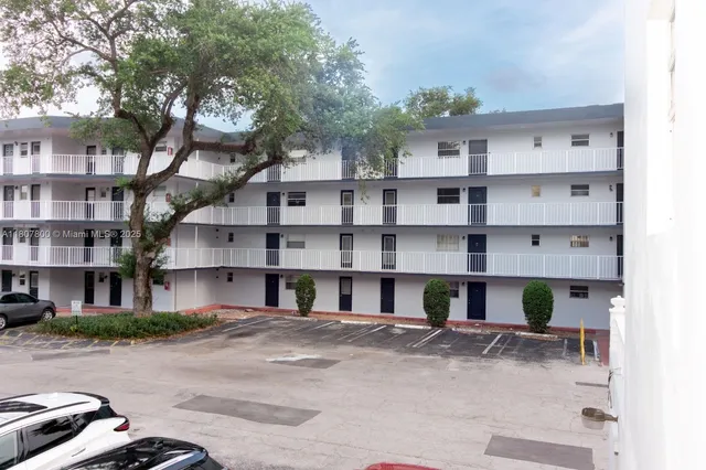 a front view of a building with streets and trees