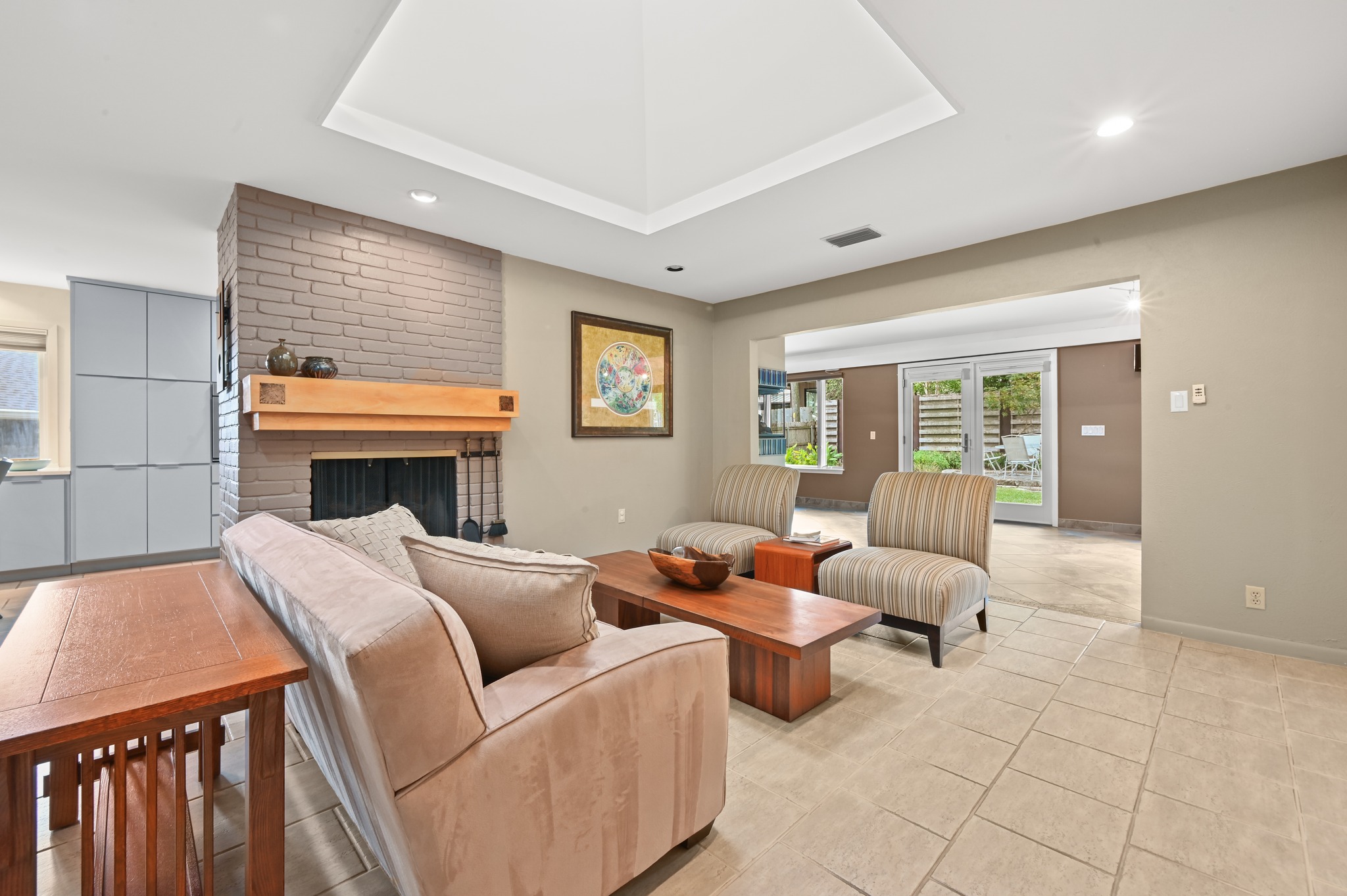 7313 Running Rope Austin, TX 78731 - Photo 5 of 26 An inviting living space features tile floors, a brick fireplace, and a tray ceiling.