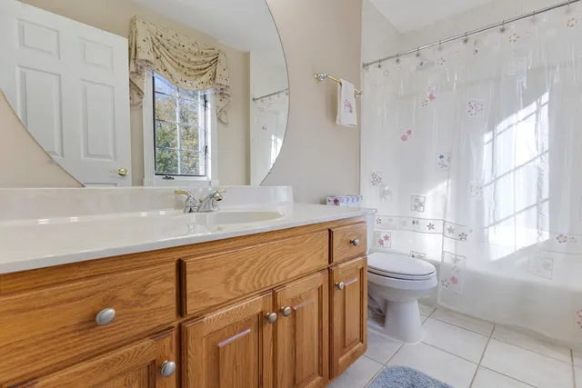 a spacious bathroom with a double vanity sink toilet mirror and bathtub