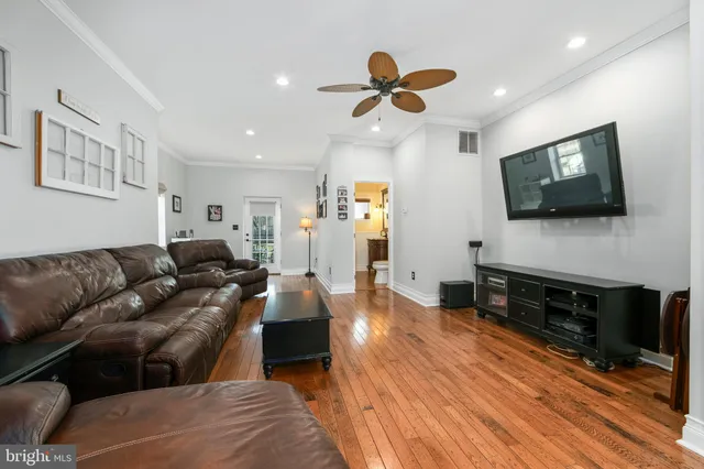 a living room with couches and kitchen view with wooden floor
