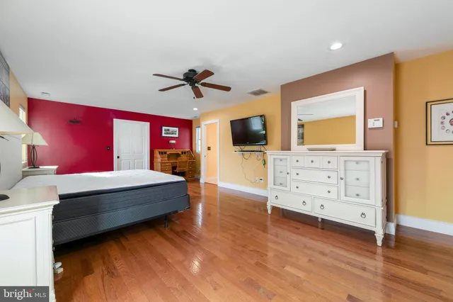 a spacious bedroom with a bed and wooden floor