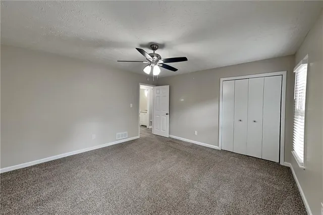 an empty room with closet and ceiling fan