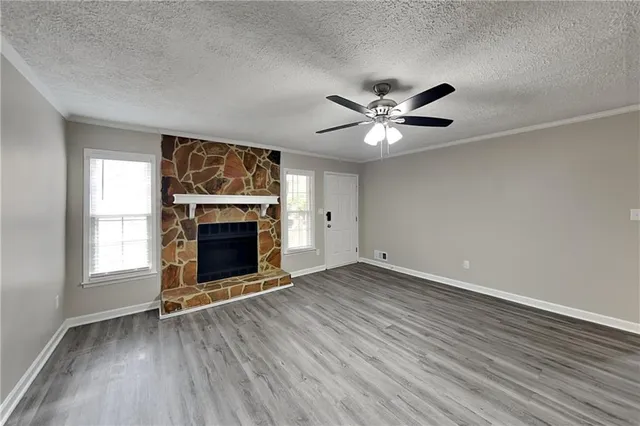 an empty room with windows a fireplace and a ceiling fan