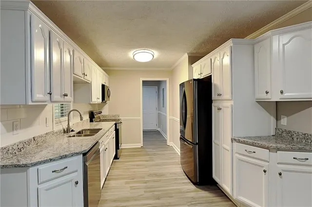 a kitchen with stainless steel appliances granite countertop a refrigerator a stove and a sink