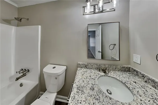 a bathroom with a granite countertop sink toilet and shower